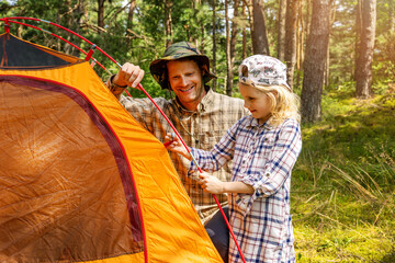 father with daughter setting up camping tent in forest. family outdoor adventure trip