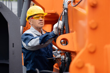 Wall Mural - Mechanic repairing hydraulic hose in drilling machine, exploration drilling. Adult man in hard hat industrial worker.