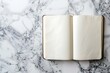© Archibalttttt - A minimalist composition featuring an open blank notebook resting on a marble surface