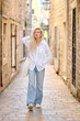 © makedonski2015 - A woman in a white blouse walks along an old narrow street in Europe