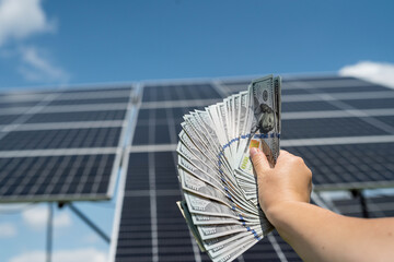 Wall Mural -  man counts the profit of the US dollar from the sale of electricity, solar panels