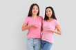 © Pixel-Shot - Young Asian women with pink ribbons on light background. Breast cancer awareness concept