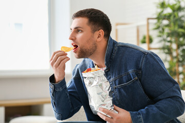 Sticker - Handsome shocked young man with tasty potato chips at home