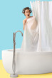 © Pixel-Shot - Shocked young woman with hair curlers behind curtain in bathtub on blue background