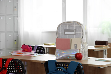 Canvas Print - Backpack with apple and water bottle on desk in classroom