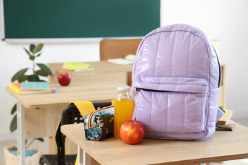 Wall Mural - Lilac backpack with apple, juice and pencil case on desk in classroom