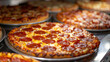 © khonkangrua - Close-up of multiple pepperoni pizzas on display, showcasing their delicious and mouth-watering appeal.