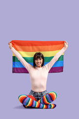 Sticker - Beautiful young woman in rainbow stockings with LGBT flag sitting on lilac background