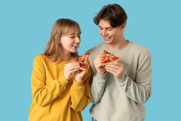 Poster - Beautiful young couple with pieces of tasty pizza on blue background