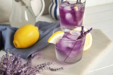 Wall Mural - Board with glasses of cold lavender lemonade and lemons on light wooden table