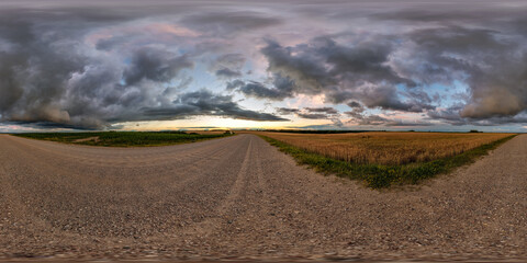 Wall Mural - hdri 360 panorama on gravel road among fields in nasty evening before sunset with dark clouds in equ
