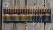 © Raul - Rows of assorted bullets neatly arranged on a wooden surface in direct sunlight.