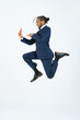 © metamorworks - Full-body photo of a black businessman jumping while looking at his smartphone