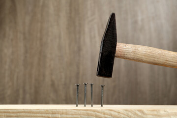 Wall Mural - Hammering nail into plank against wooden background, space for text