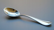 © RISHAD - Shiny metal spoon placed on a plain surface, reflecting light, showcasing its smooth and polished design.