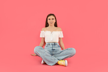 Canvas Print - Attractive young girl sits on a pink background