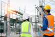 © sirichai - Civil Engineer women and foreman in safety suite with blueprints collaboration to work inspection building structure on factory construction site, contractor and development real estate concept.