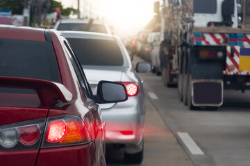 Wall Mural - Rear side of red car on the road. Concrete road with many car during time on traffic jam. Speed light lines on the tail lights. Car parked in a long queue.