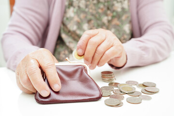 Retired elderly woman counting coins money and worry about monthly expenses and treatment fee payment.