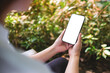 © Farknot Architect - Mockup image of a woman holding mobile phone with blank white desktop screen in the outdoors
