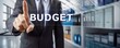 © Stocks Buddy - A businessman in suit pointing at virtual word budget showing budget concept