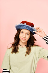 Wall Mural - A stylish teenage girl in a striped shirt and hat poses confidently in vibrant attire.