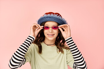 Wall Mural - A stylish teenage girl strikes a pose in vibrant attire, wearing sunglasses and a hat.