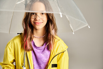 Wall Mural - A stylish teenage girl in vibrant attire holds a clear umbrella over her head in an active pose.