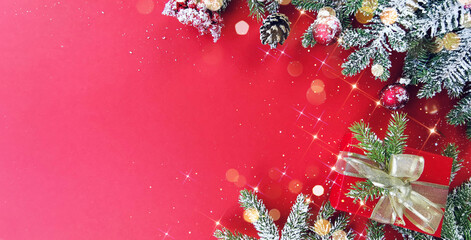 Wall Mural - christmas decorations concept. border of snow-covered fir branches, trinkets and trinkets on a red b