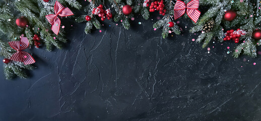 Wall Mural - beautiful dark christmas background with a border of fir branches and red decorations. black greetin