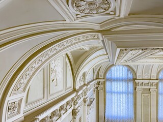 An elegant ceiling adorned with detailed molding and classical design elements in a historic building. The intricate craftsmanship and ornate decorations highlight the grandeur of the interior space