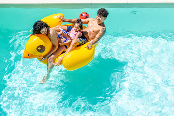 Family enjoys a fun pool day on an inflatable duck, smiling and playing together.