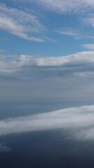 Wall Mural - aerial view. blue sky sun and fog over calm sea. the drone flies over foggy and fluffy clouds. abstr