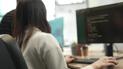 female software developer writing code in modern office, rear view of woman programmer working on co