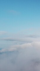 Wall Mural - aerial vertical view over foggy and fluffy clouds. blue sky sun, sea fog. abstract nature summer oce