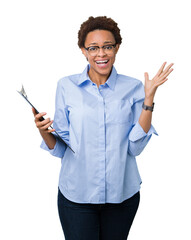 Wall Mural - Young african american businesss woman holding clipboard over isolated background very happy and excited, winner expression celebrating victory screaming with big smile and raised hands