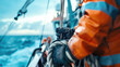 © Anna - Fisherman wearing orange rain gear pulling rope on a fishing vessel in rough sea. Commercial fishing industry, maritime work, ocean exploration, extreme weather conditions.