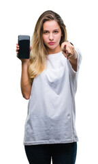 Wall Mural - Young beautiful blonde woman showing screen of smartphone over isolated background pointing with finger to the camera and to you, hand sign, positive and confident gesture from the front