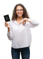 Sticker - Young hispanic woman holding passport of United States of America with surprise face pointing finger to himself