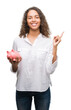 © Krakenimages.com - Young hispanic woman holding piggy bank very happy pointing with hand and finger to the side