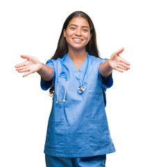 Wall Mural - Young arab doctor surgeon woman over isolated background looking at the camera smiling with open arms for hug. Cheerful expression embracing happiness.