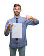 © Krakenimages.com - Young handsome man holding blank paper over isolated background with surprise face pointing finger to himself