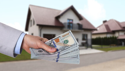 Wall Mural - Woman holding money against beautiful house, closeup. Real estate purchase