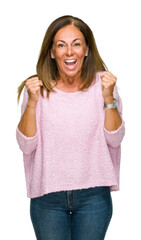 Canvas Print - Beautiful middle age adult woman wearing winter sweater over isolated background celebrating surprised and amazed for success with arms raised and open eyes. Winner concept.