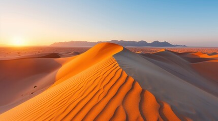 An enchanting capture of rolling sand dunes bathed in the serene glow of the setting sun, portraying an endless expanse of soft, undulating shapes under a clear sky.