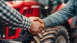 © liliyabatyrova - Two men shake hands in front of a red tractor, signifying a successful purchase