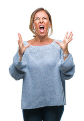 Wall Mural - Middle age senior hispanic woman wearing winter sweater over isolated background crazy and mad shouting and yelling with aggressive expression and arms raised. Frustration concept.