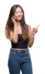 Wall Mural - Young asian woman speaking on the phone over isolated background very happy pointing with hand and finger to the side