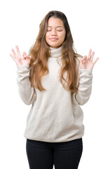 Sticker - Young beautiful brunette woman wearing turtleneck sweater over isolated background relax and smiling with eyes closed doing meditation gesture with fingers. Yoga concept.