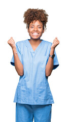 Wall Mural - Young african american doctor woman over isolated background celebrating surprised and amazed for success with arms raised and open eyes. Winner concept.